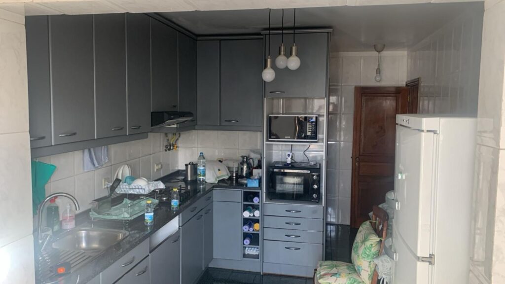 Vista de uma cozinha antiga antes da remodelação, com móveis desatualizados e pouco funcionais